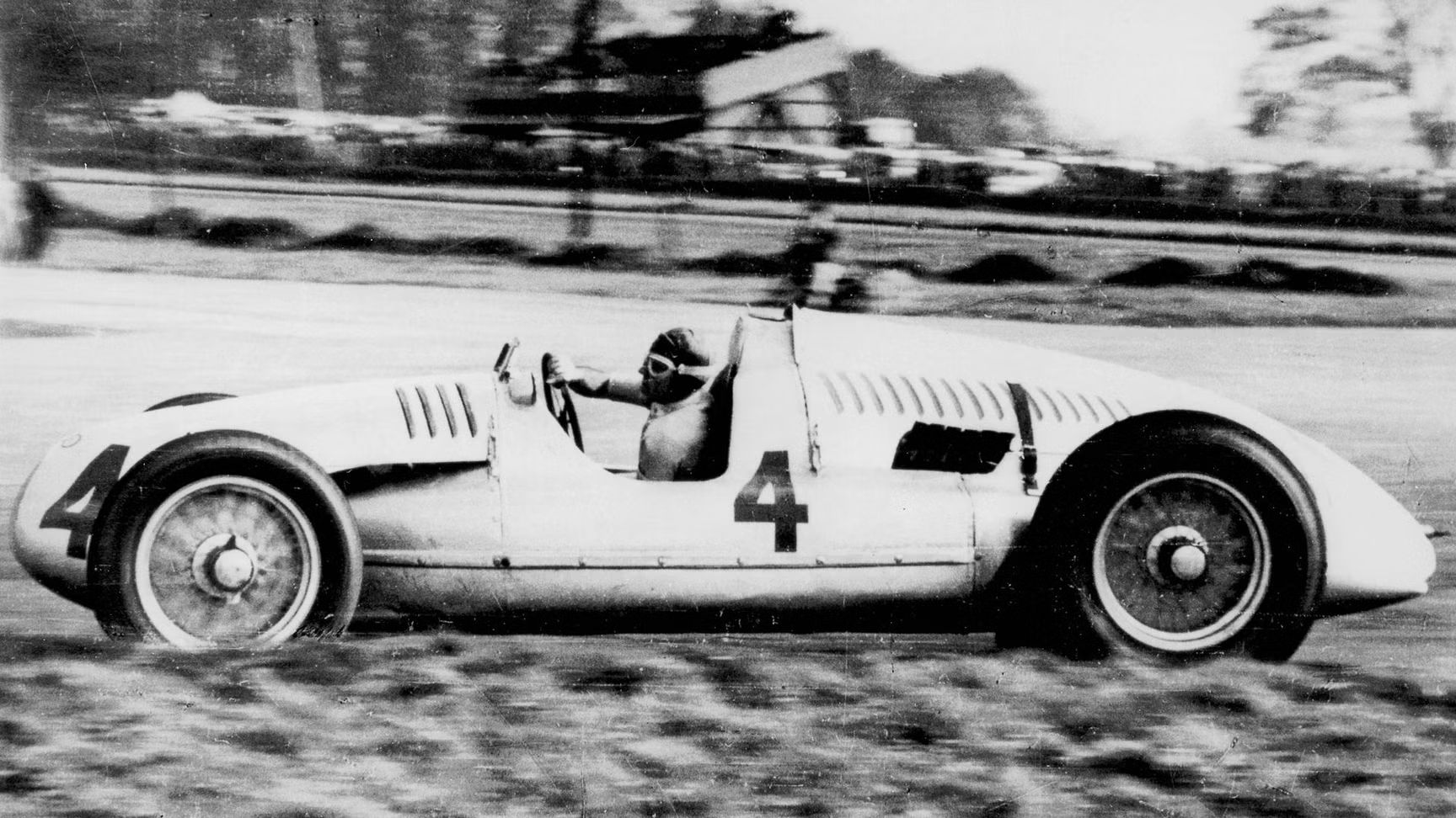 Történelmi fotó Tazio Nuvolari versenyzőjéről egy Auto Union Grand Prix versenyautóban.