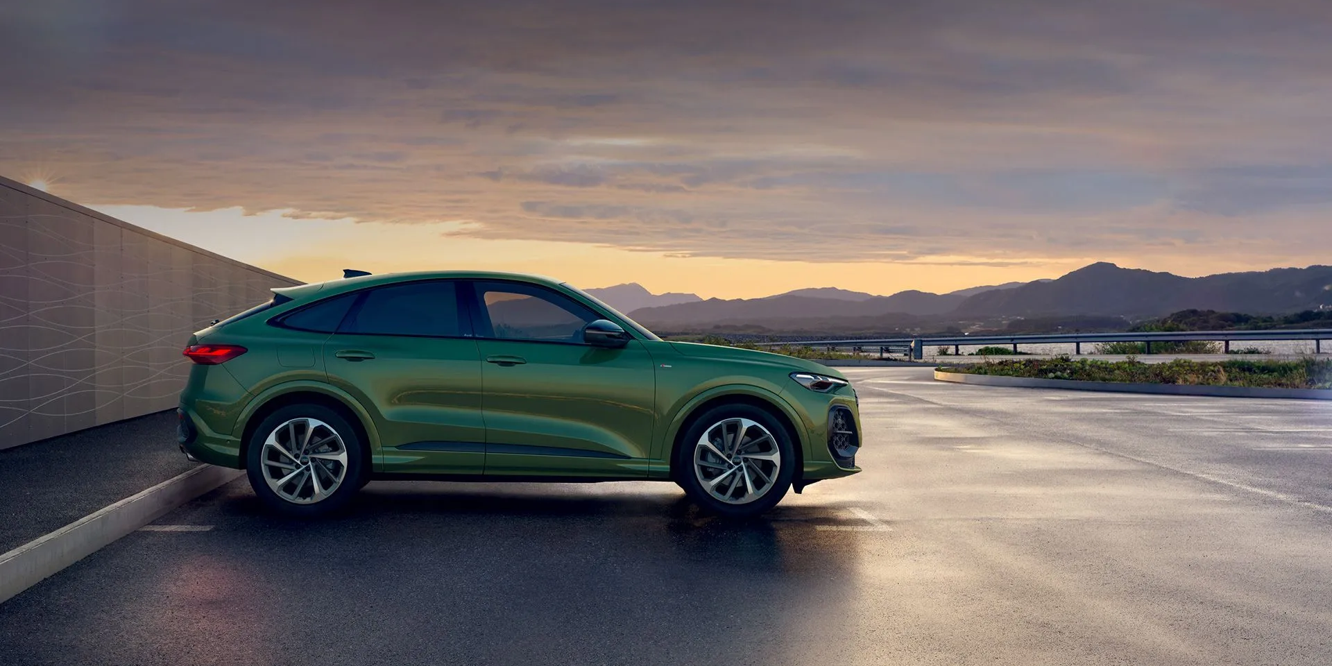 Zöld Audi Q5 oldalról a naplementében