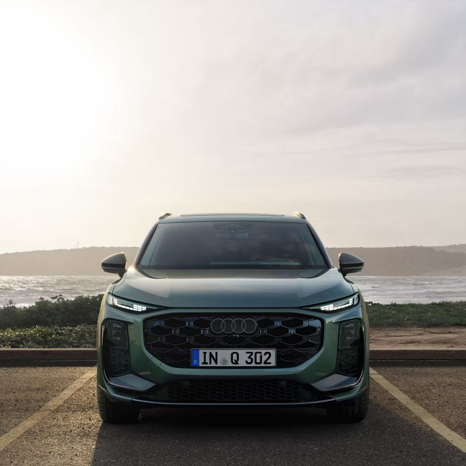 Audi Q3 terepjáró elölről egy víztömeg előtti parkolóban