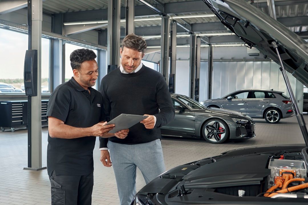 két szervizes férfi beszélget egy táblagép fölött