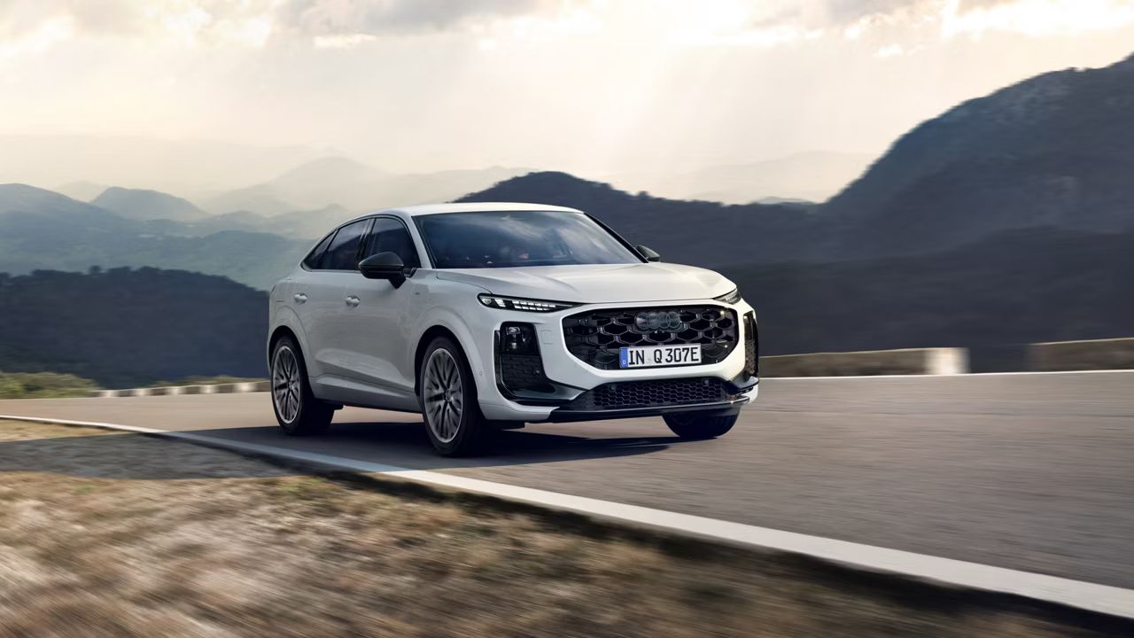 Audi Q3 Sportback e-hybrid auf einer Landstraße. Das weiße Auto fährt durch eine bergige Landschaft. 