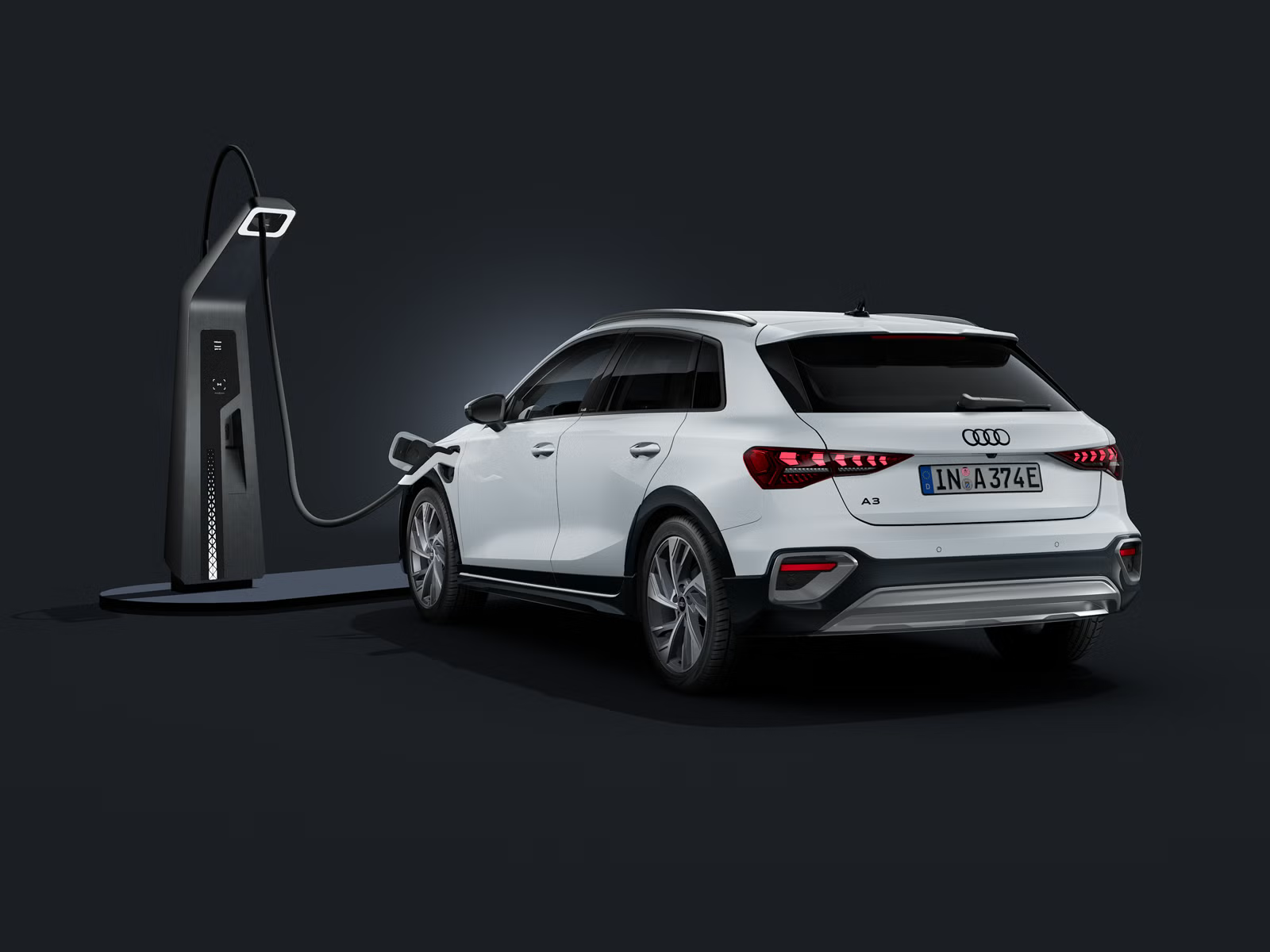 Der Audi A3 allstreet e-hybrid schräg von hinten auf dunklem Hintergrund, angeschlossen an eine moderne Ladesäule.