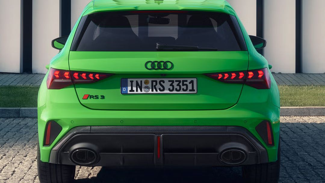 Ein grüner Audi RS 3 Sportback parkt vor einem Gebäude.